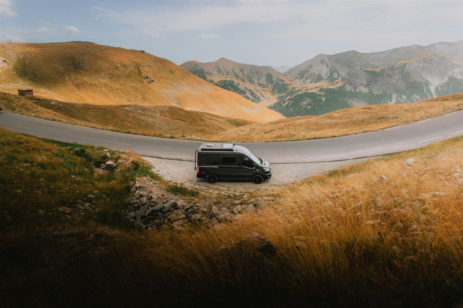 Un van aménagé sur une route de montagne dans les Alpes